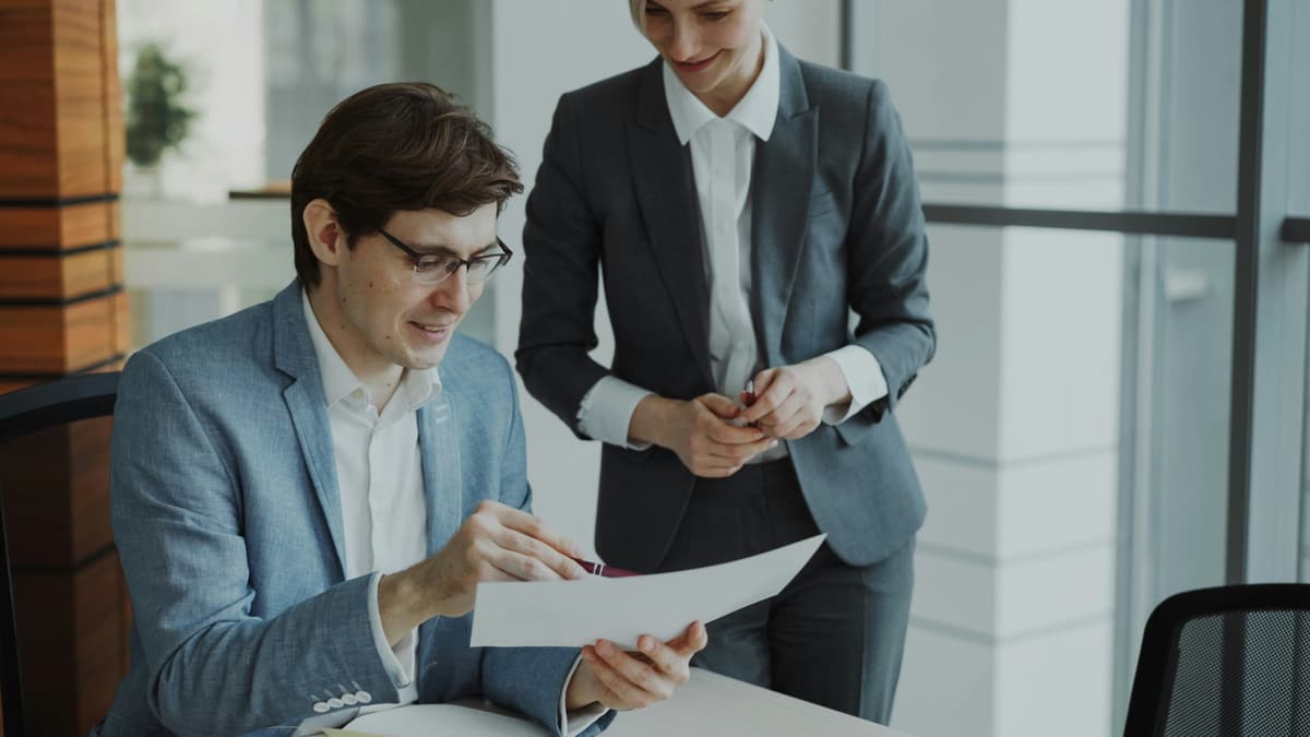 Trade advisor reviewing deal paperwork with a counterpart across a desk